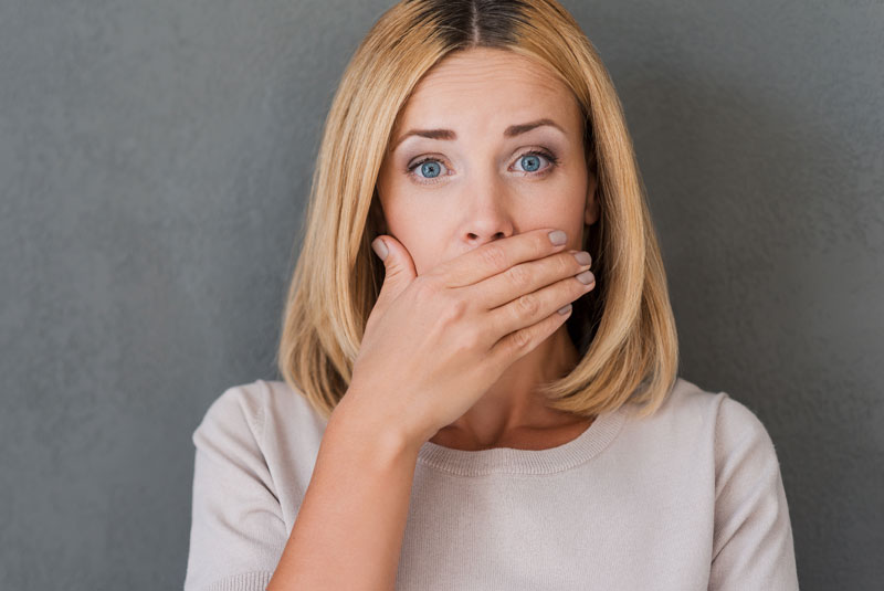 Dental Patient Hiding Her Missing Tooth During A Dental Implant Consultation