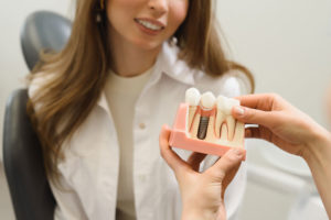 Dental Patient Getting Shown A Dental Implant Model During Her Consultation in New York, NY