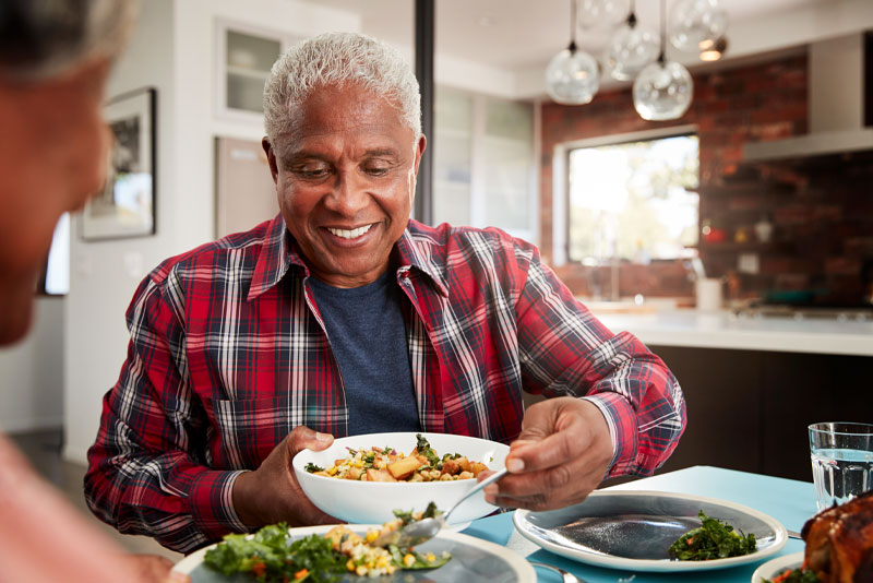 a dental implant patient smiling over dinner because he got his dental implants placed by a skilled periodontist.