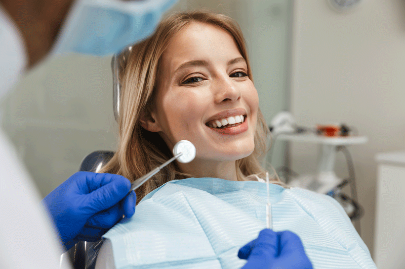 Image of beautiful woman sitting in dental chair while professional doctor fixing her teeth
